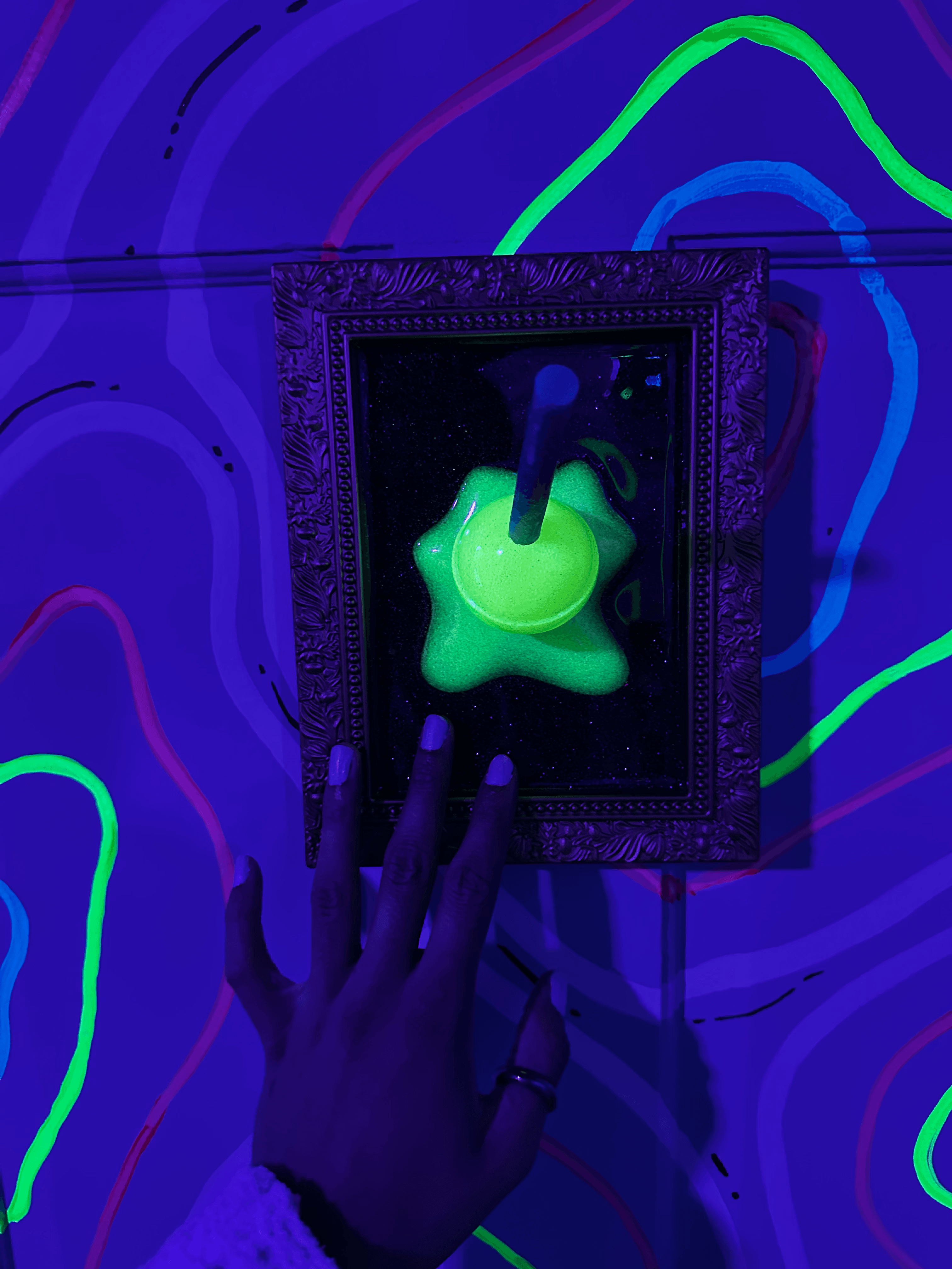 An abstract mixed media artwork with neon green and blue elements against a dark background, framed.