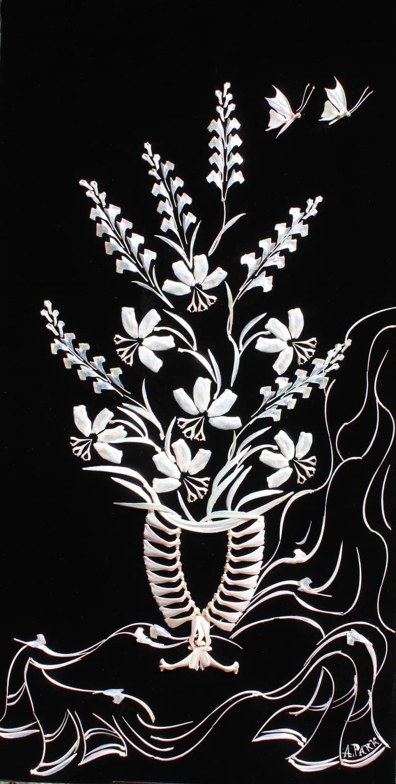 A mixed media artwork features delicate white floral arrangements and butterflies against a black background, with inlaid details.