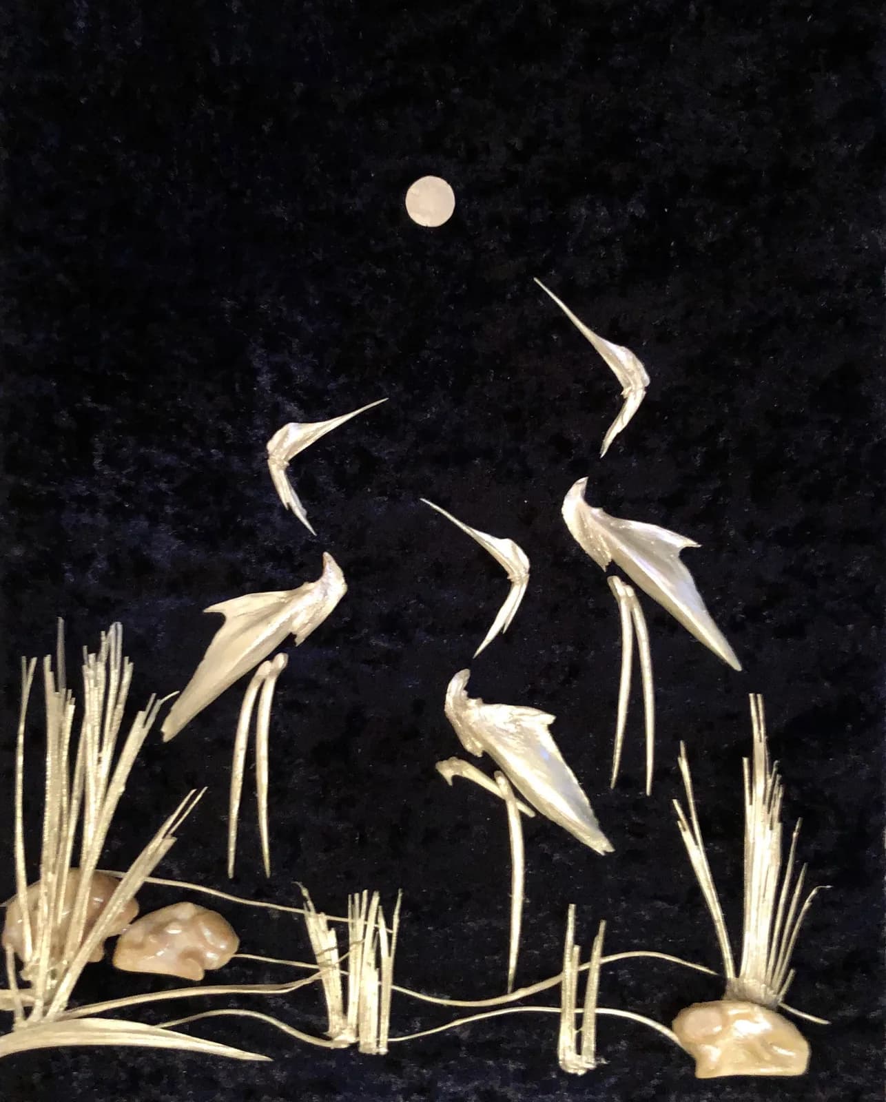 A mixed media artwork depicts cranes under a moonlit sky with reeds and stones in the foreground.