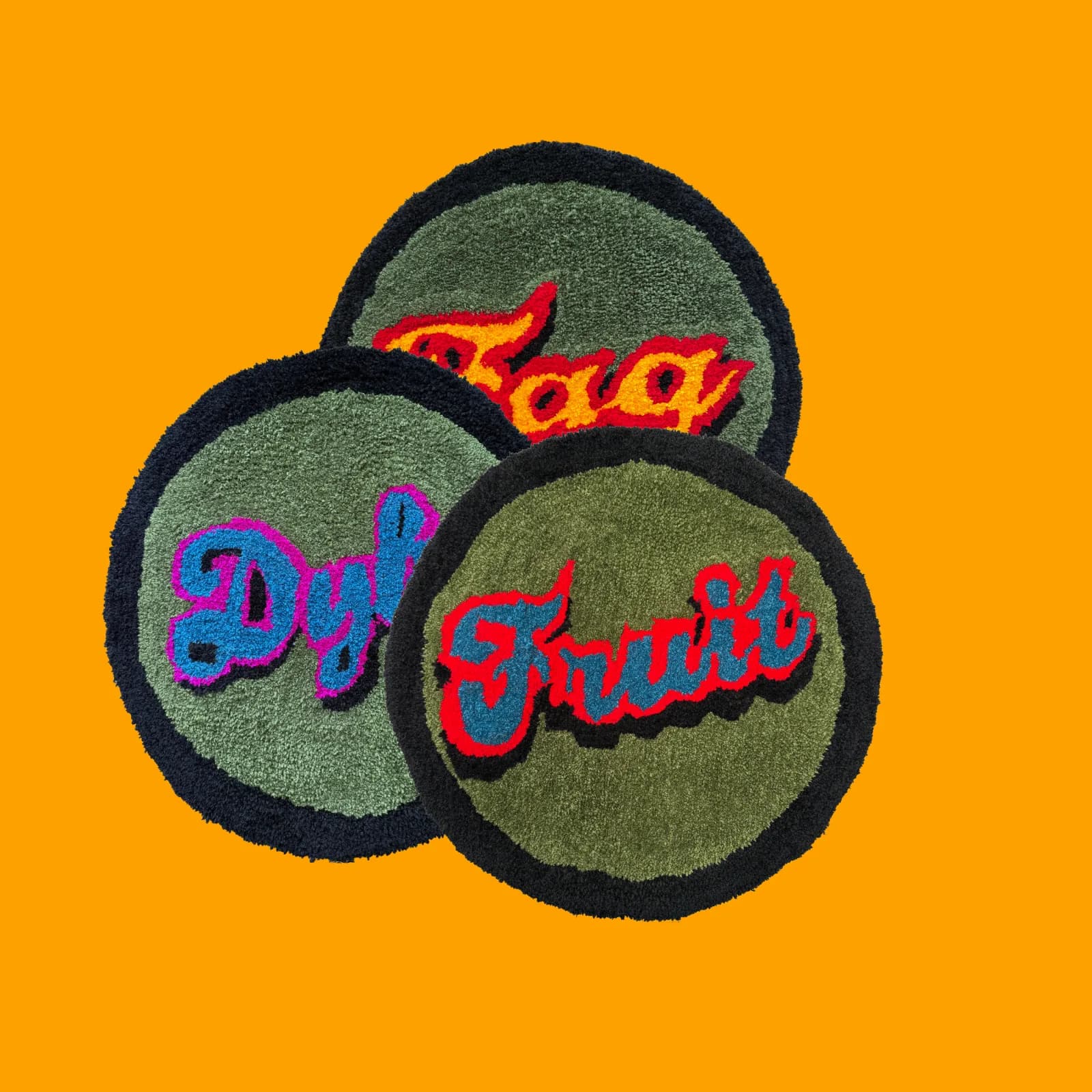 Three circular fiber art pieces with embroidered text in bold colors on a green background.