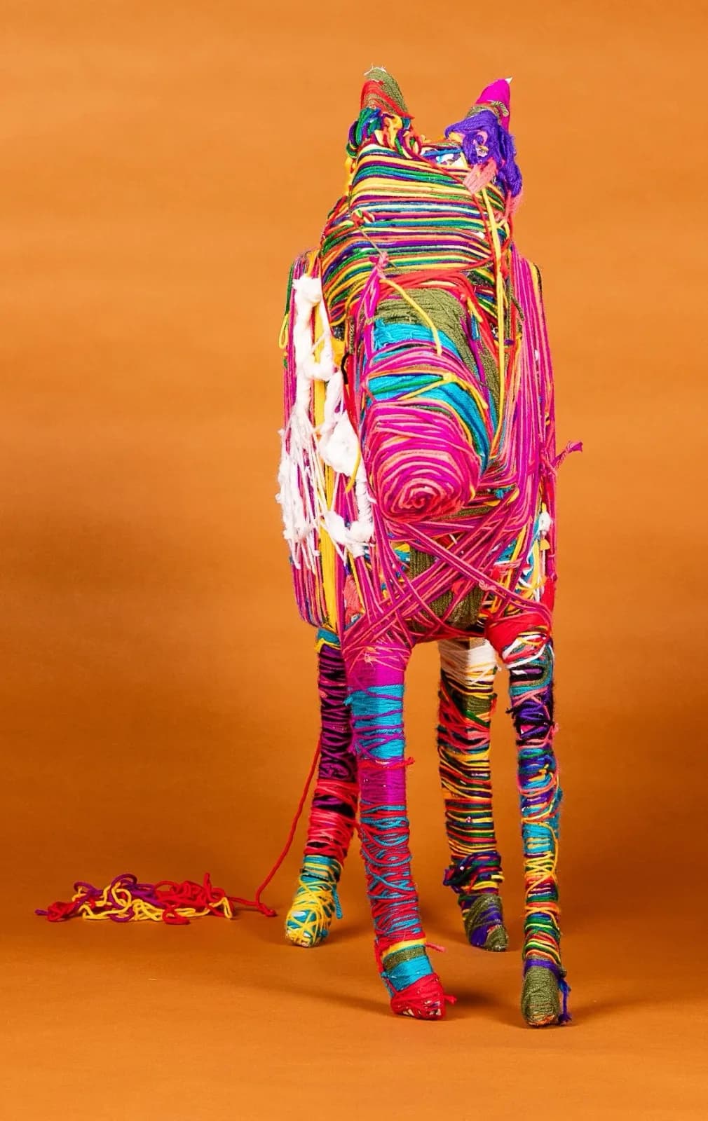 A colorful yarn-wrapped horse sculpture made of fiber on a Jaffa background.