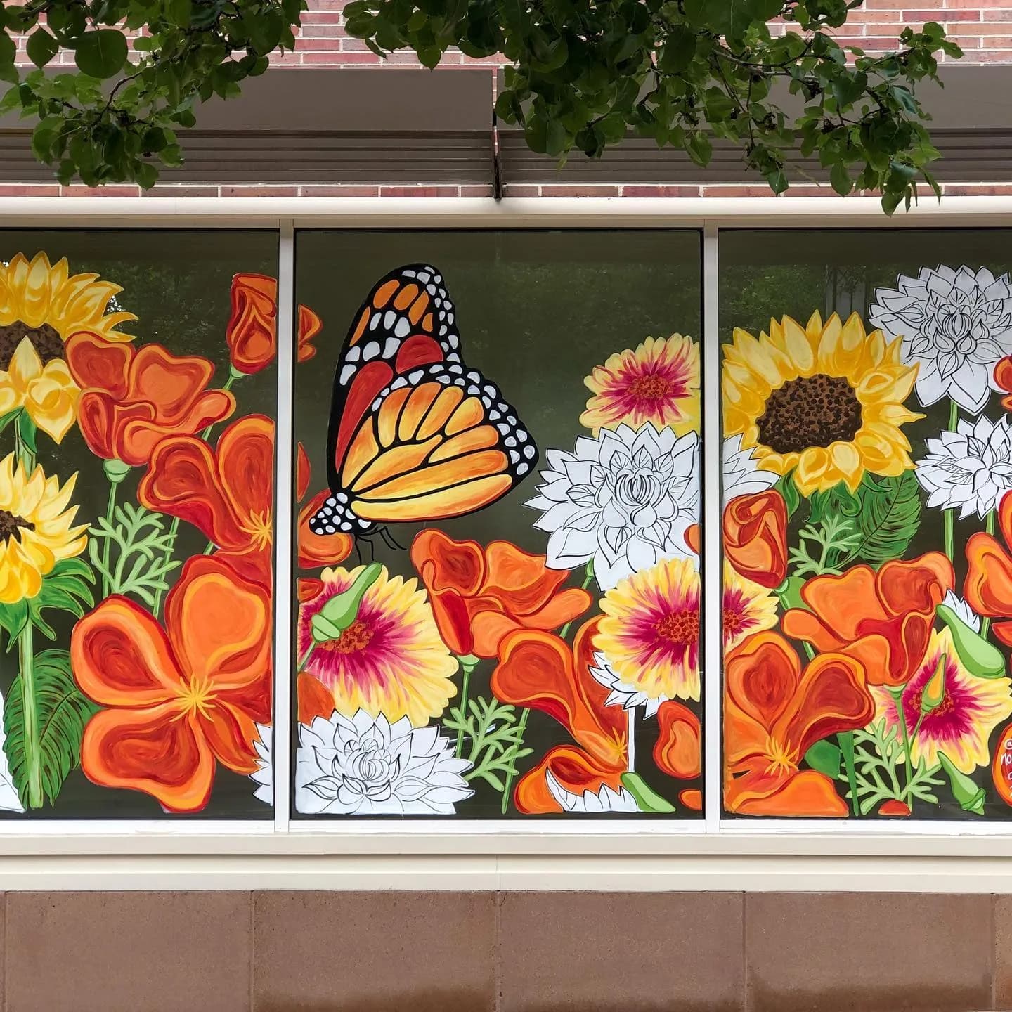 A monarch butterfly rests among vibrant orange poppies and sunflowers, painted in oil and acrylic.