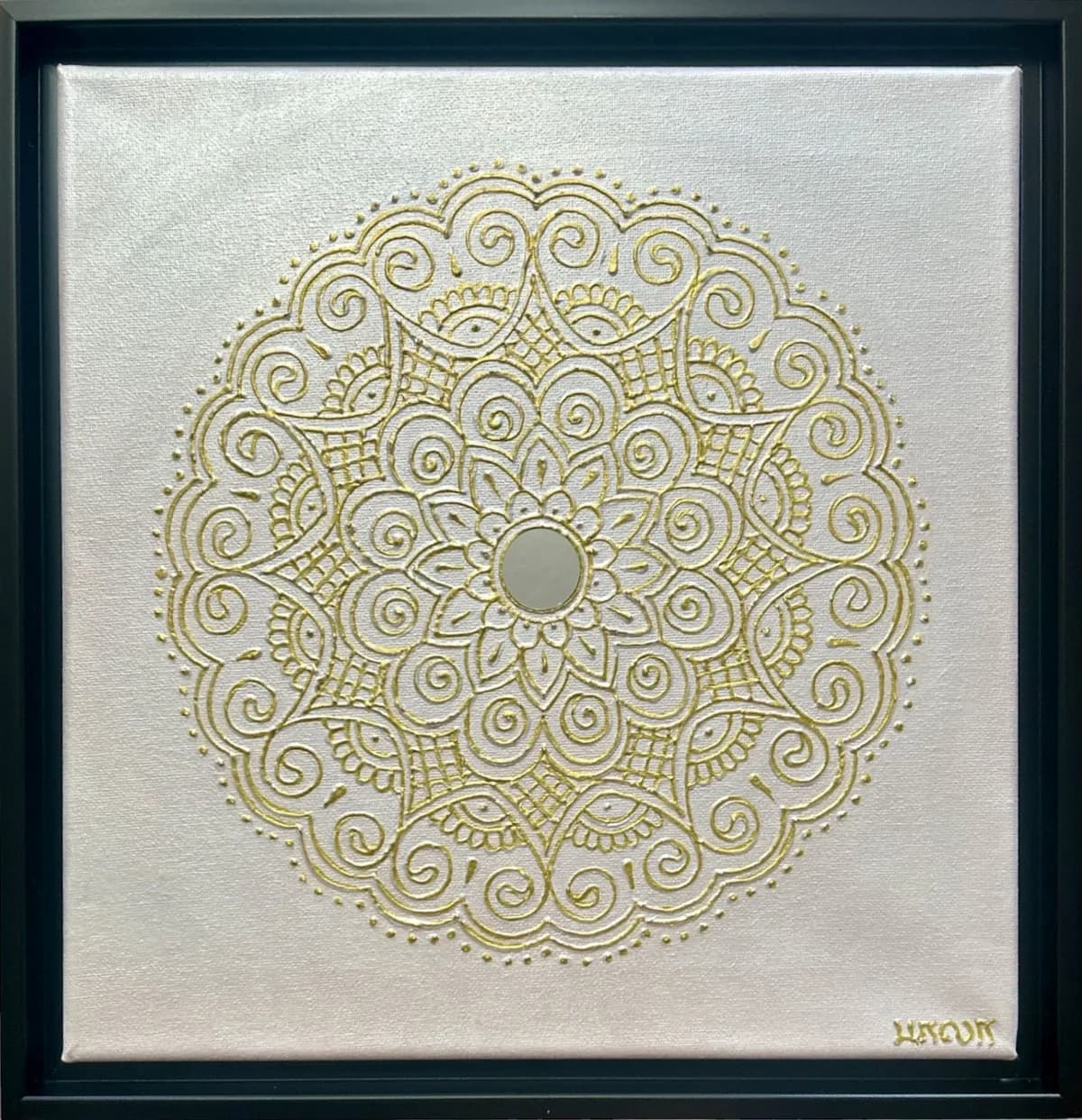 A geometric mandala artwork with gold embossed details and a central mirror on a light gray background.