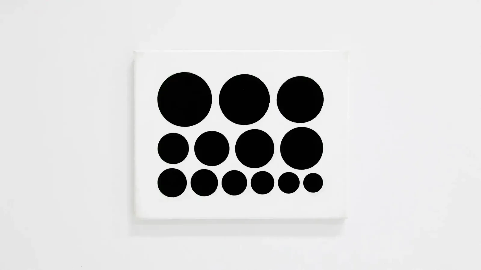 A painting of black circles of varying sizes arranged in rows on a white canvas.