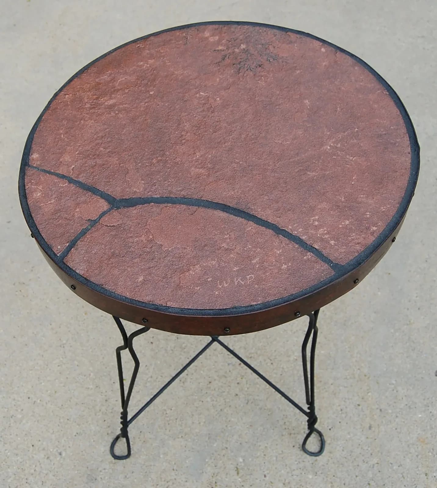 A decorative metal table with a stone top, featuring a textured surface in Tide and Opium hues.