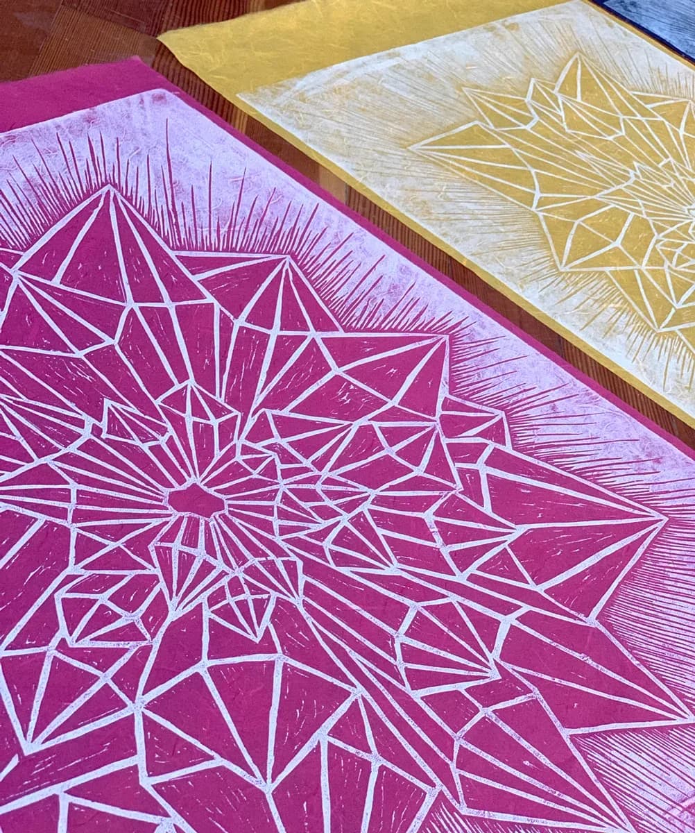 A geometric starburst print in Wisteria and white on paper, featuring intricate angular designs.