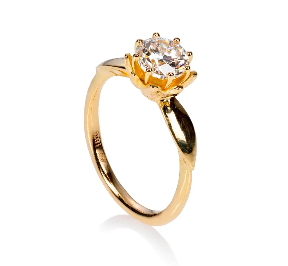 A gold ring with a prominent diamond, featuring a unique floral-inspired setting.