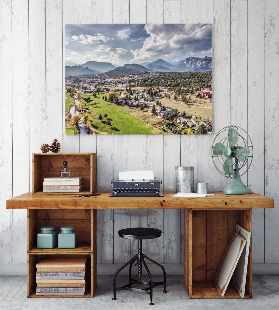 A landscape photograph captures the town of Estes Park with the Flatirons mountains under a dramatic sky.