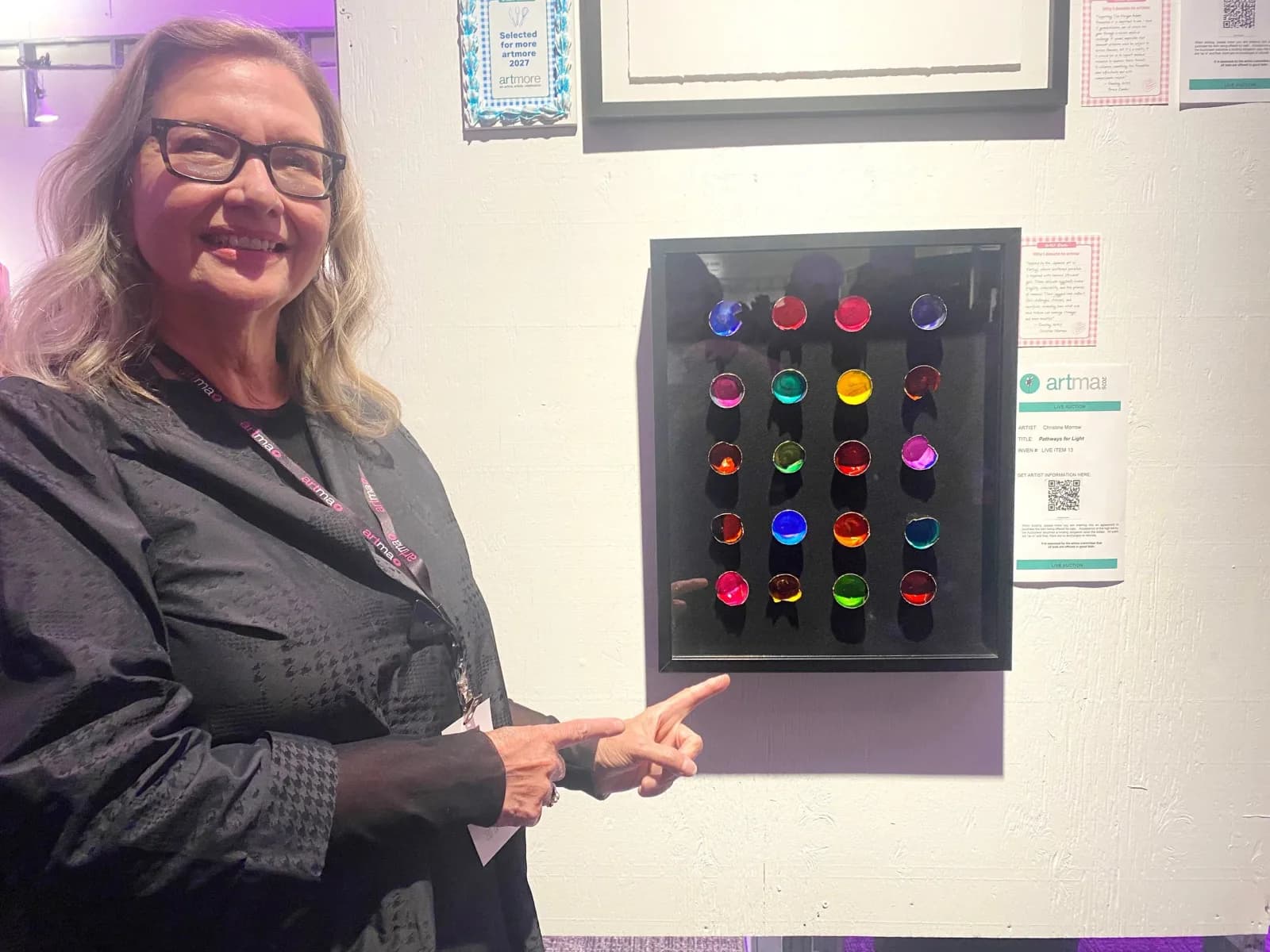 A framed mixed media artwork features 25 colorful glass orbs arranged in a grid against a dark background.
