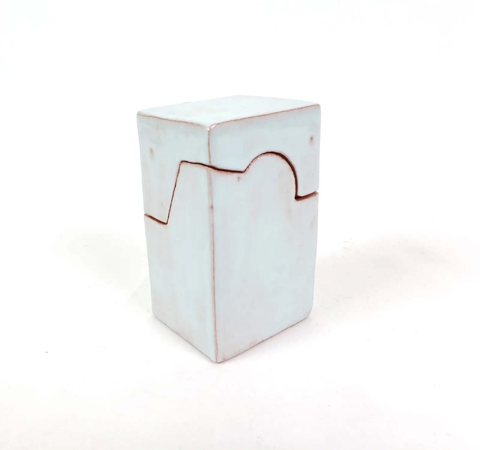 A light blue ceramic puzzle box with a unique interlocking design sits on a white background.