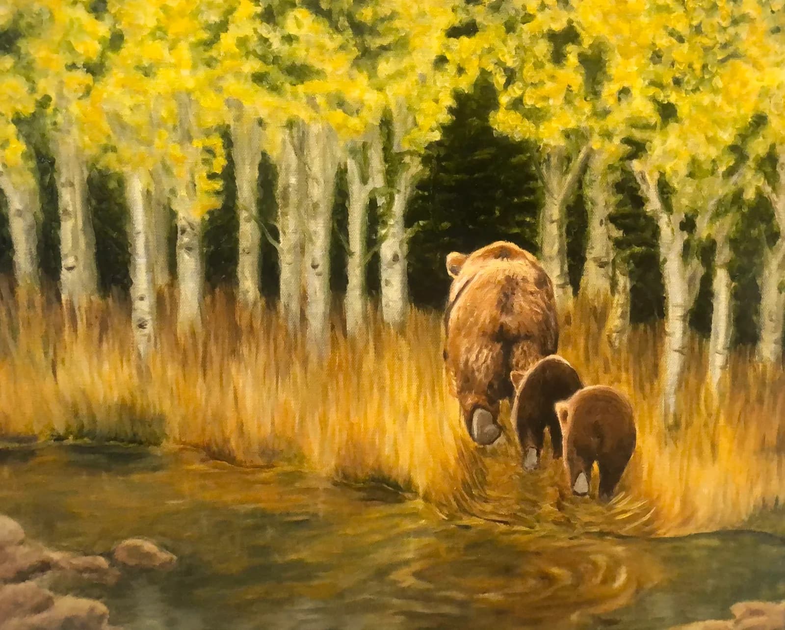 A mother bear and her cubs walk through a golden aspen forest beside a stream in this oil painting.