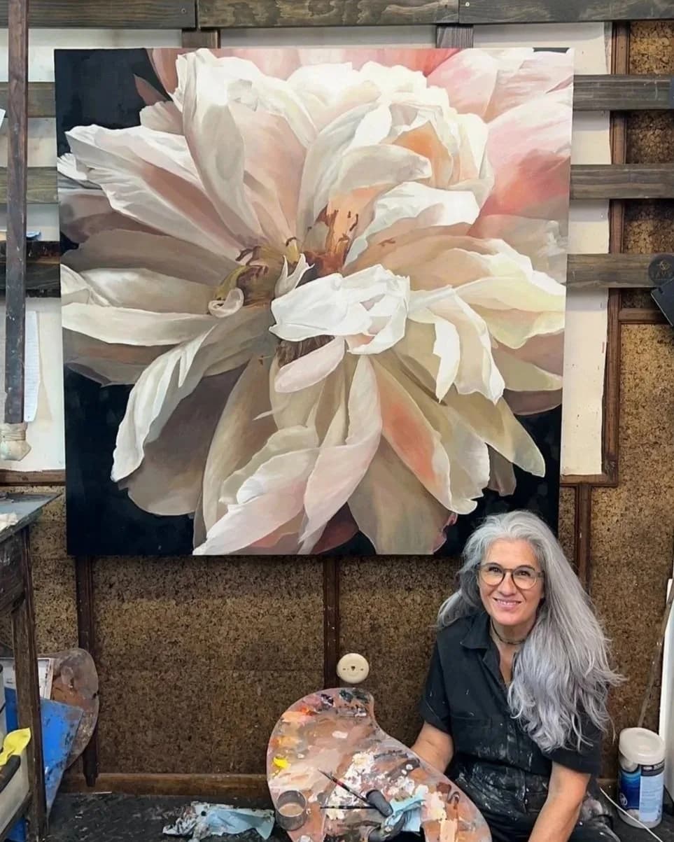 A large painting of a pale pink and white peony is shown in situ in an artist's studio with the artist present.