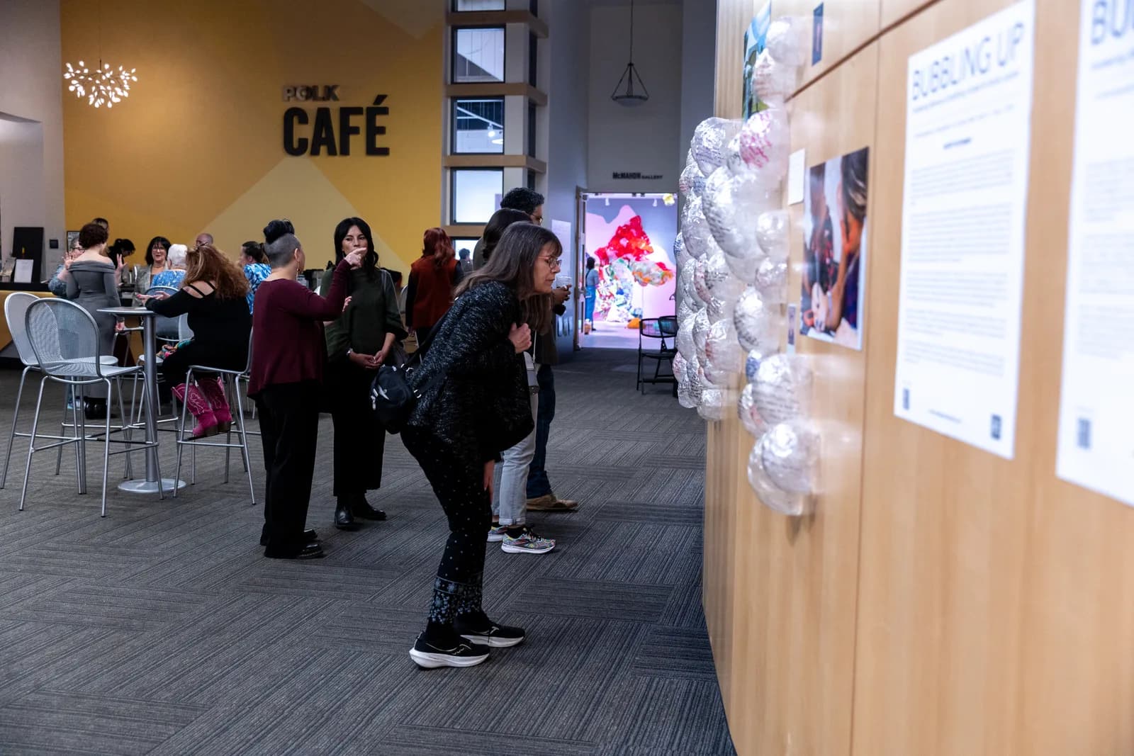 People viewing an art installation in a gallery space with text panels.