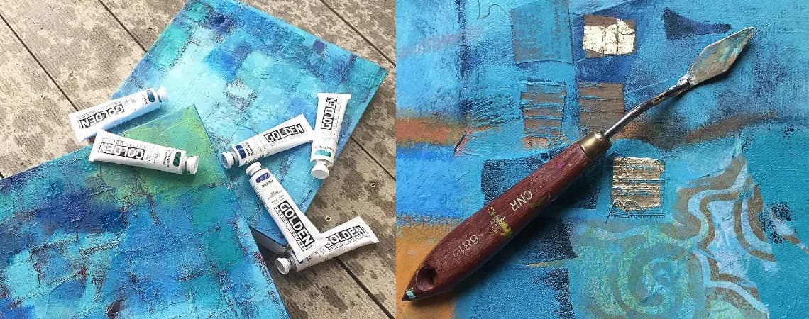 Abstract painting process with tubes of paint and a palette knife on a textured blue and gold surface.