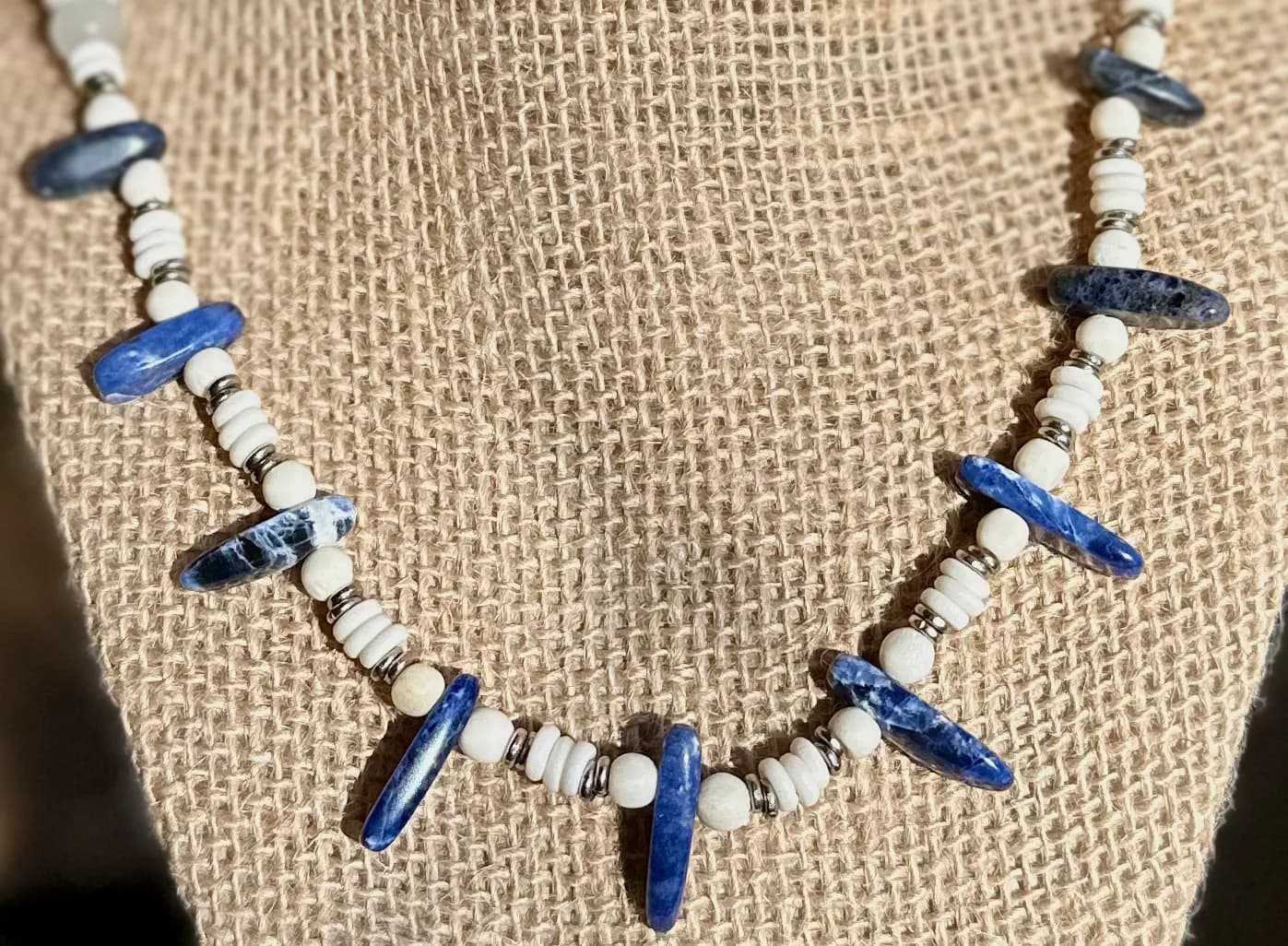 A beaded necklace featuring blue and white stones, crafted with a unique artistic design.