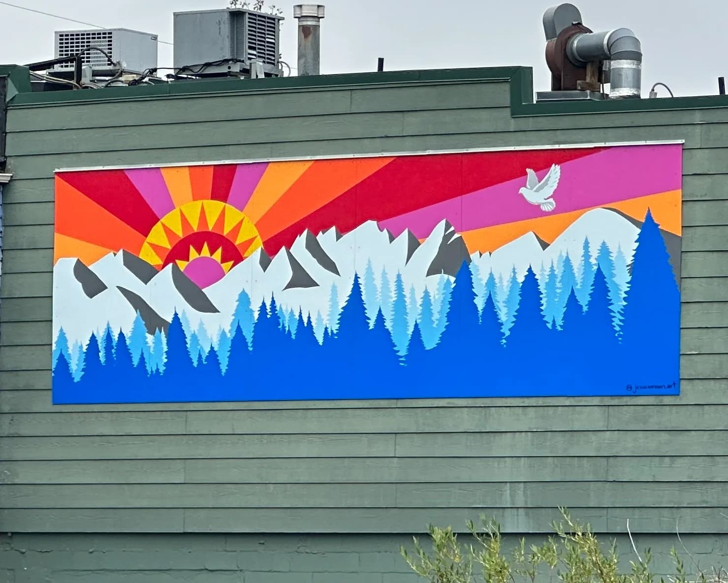 A vibrant mural depicts a stylized sunrise over snow-capped mountains and a forest, with a dove in flight.