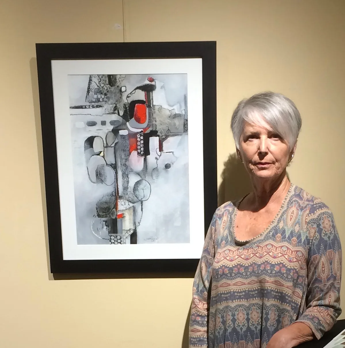 An abstract mixed media painting in shades of grey, white, and red, featuring geometric shapes and organic forms.