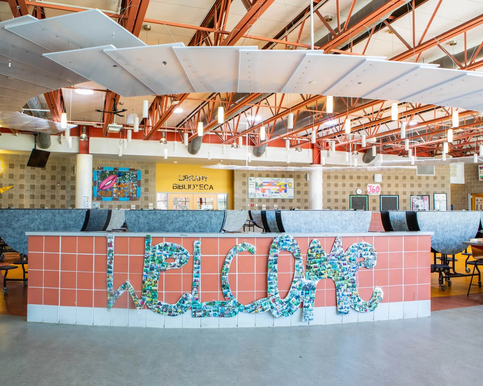 A mosaic spelling "Welcome" in colorful tiles adorns a coral-tiled wall in a library.