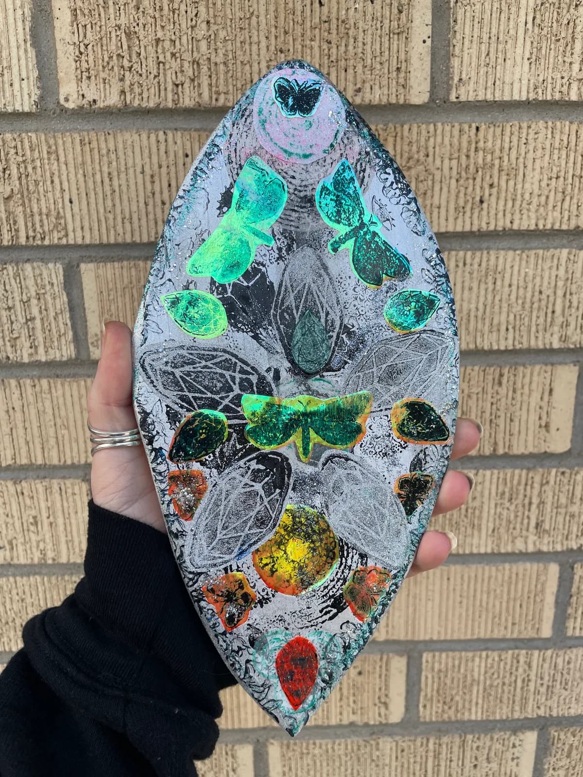 An abstract mixed media artwork featuring butterflies and natural elements in shades of Shamrock, Mongoose, and Bunker.