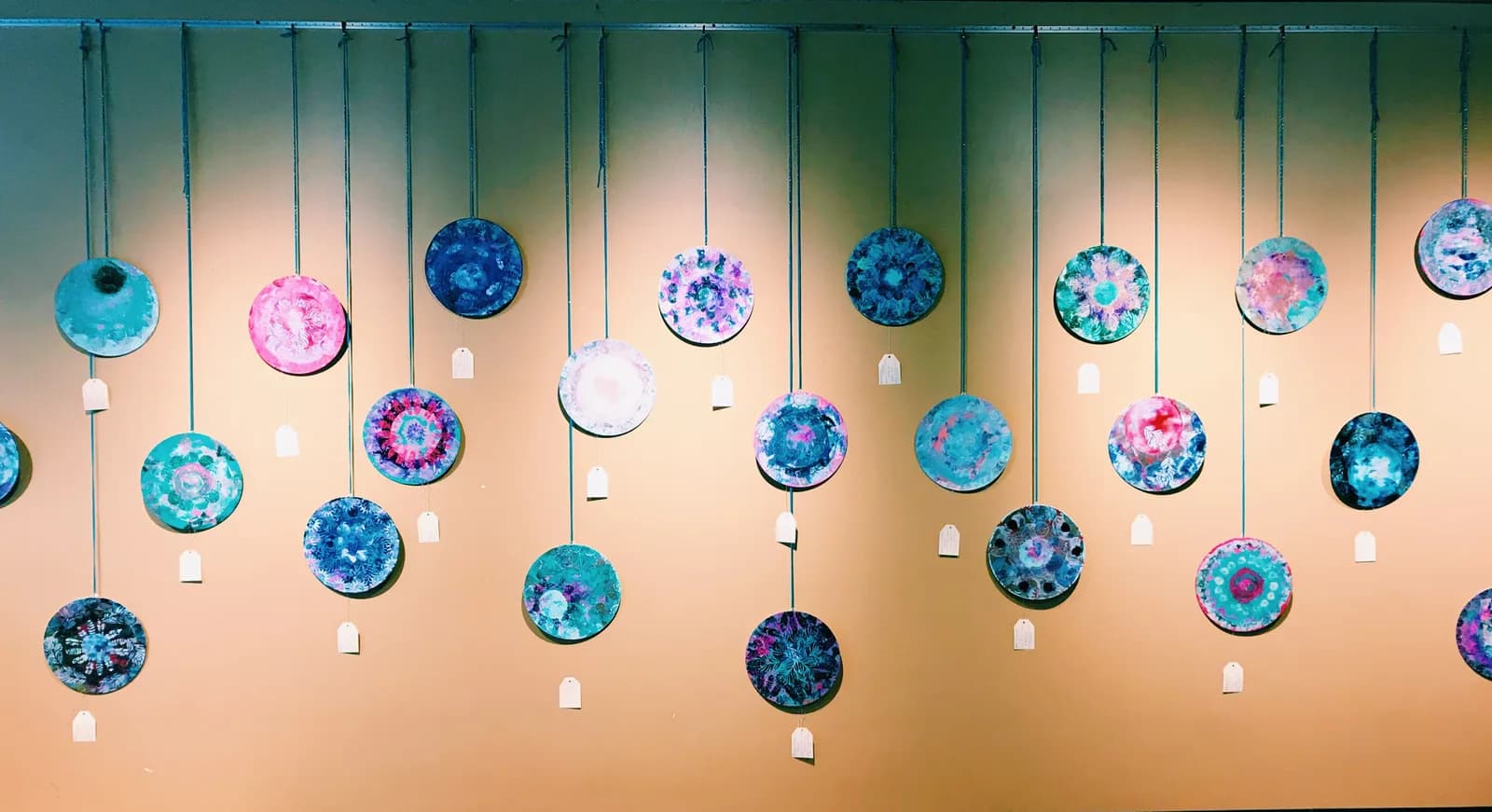 Abstract circular mixed media artworks in shades of Glacier, Almond, and Clay Creek hang against a warm wall.
