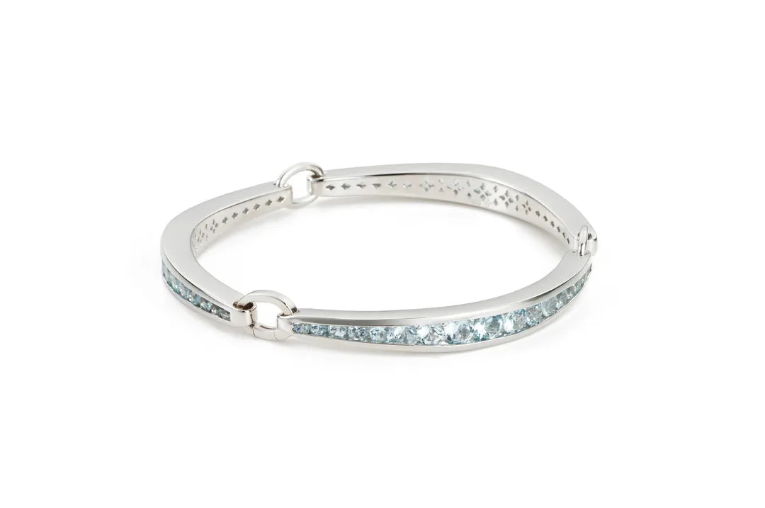 A silver bracelet with aquamarine stones is presented against a white background.