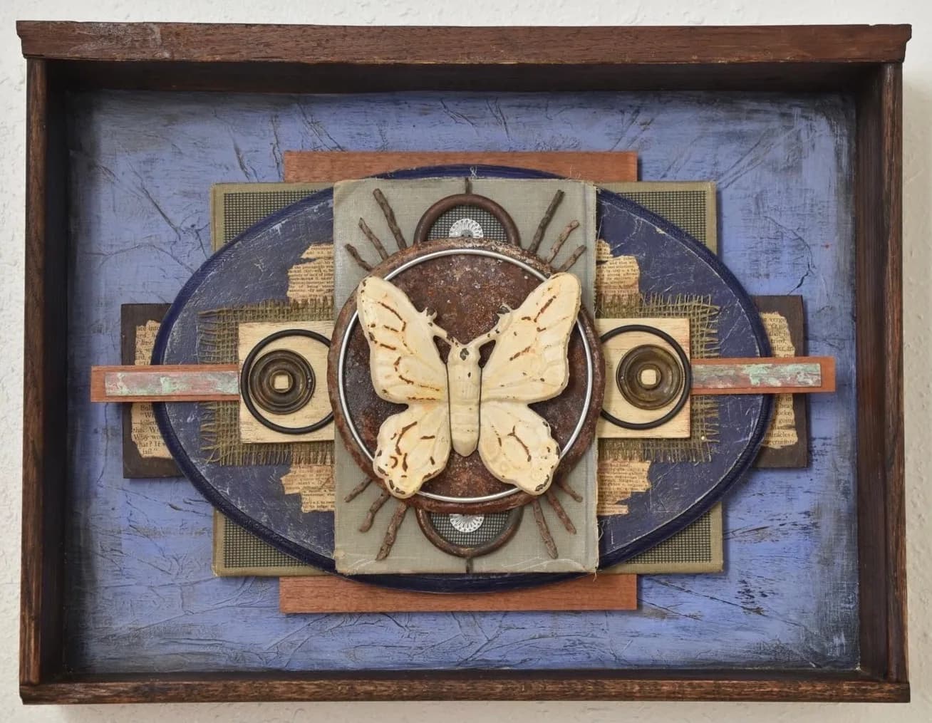 A mixed media assemblage featuring a butterfly and found objects in shades of Roman Coffee and Shark.