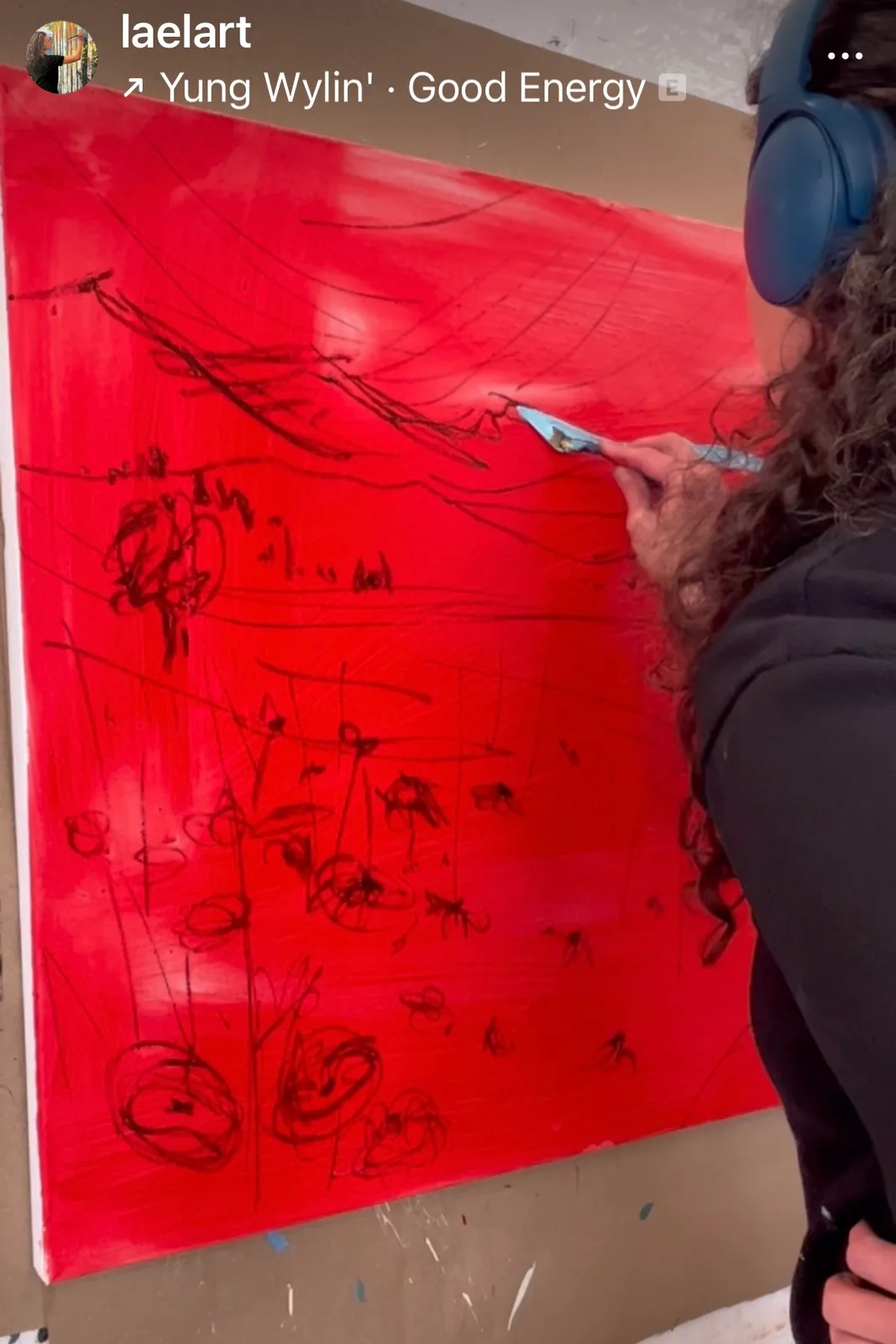 An artist works on a large red abstract painting with black ink sketches.