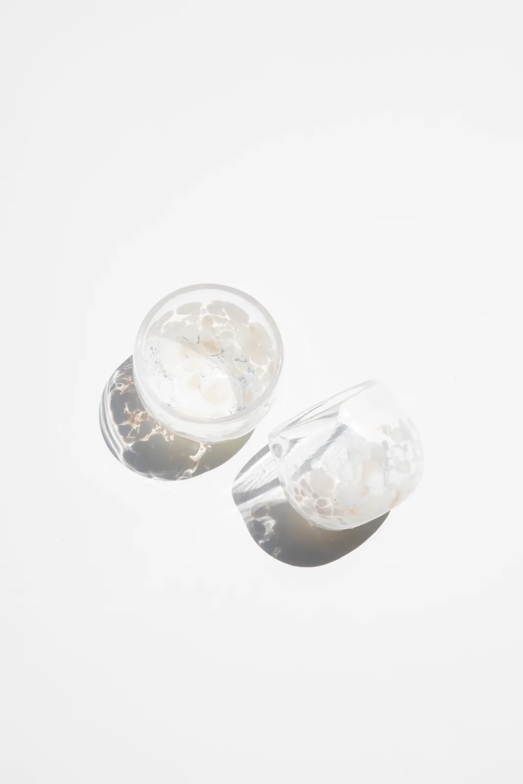 Two decorative glass vessels with a speckled pattern, presented on a neutral background.