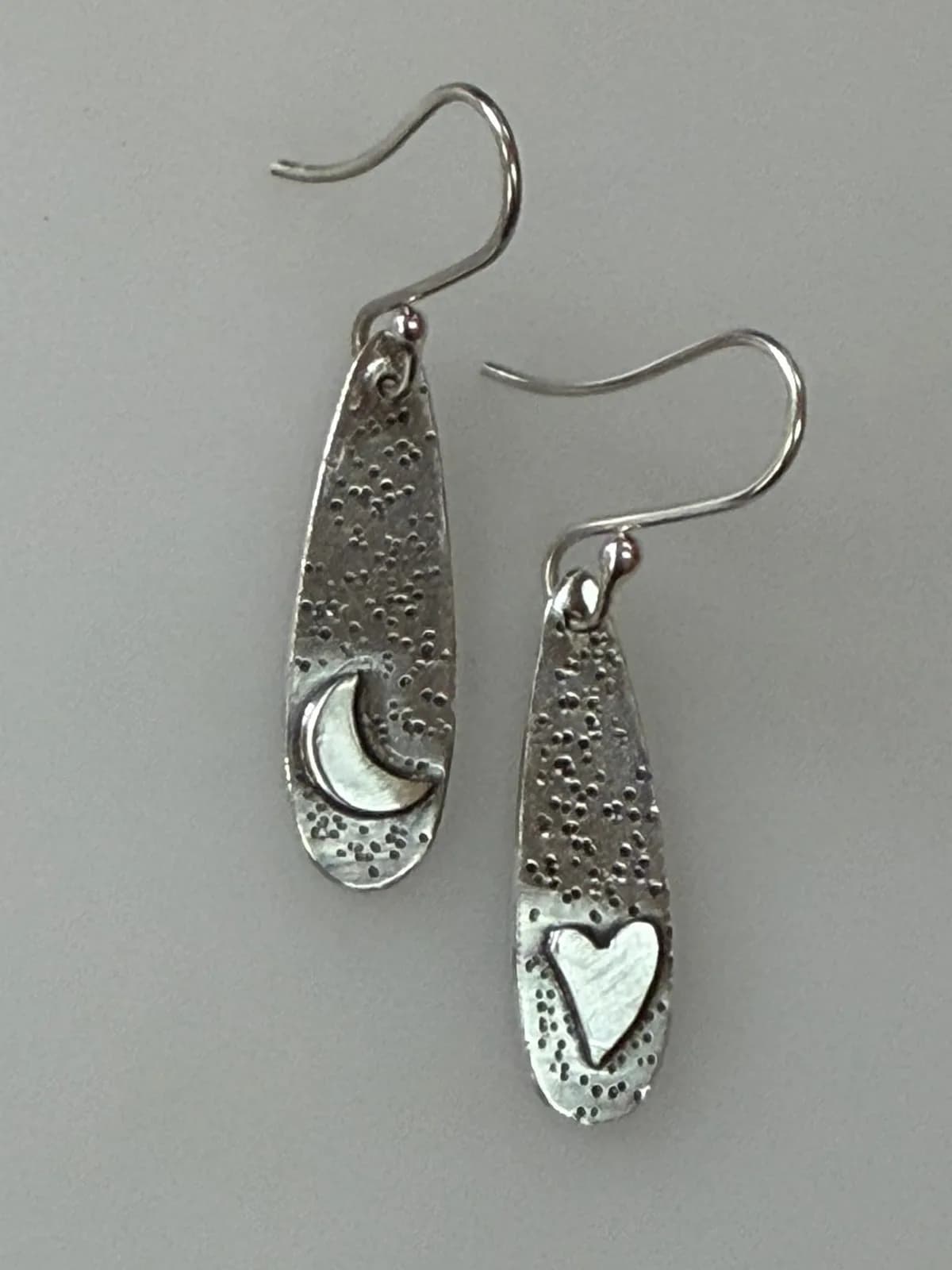Sterling silver earrings featuring a crescent moon and a heart motif with a textured background.