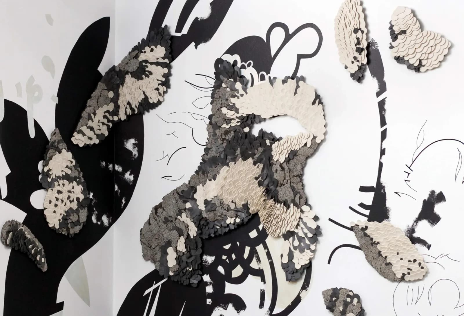 A mixed media paper artwork features abstract textured forms in black and white against a graphic background.