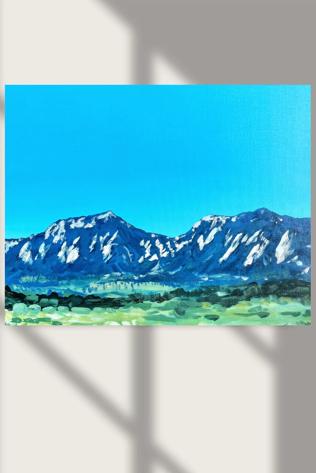 An impressionistic oil painting depicts the Flatirons mountains under a bright azure sky with green fields in the foreground.