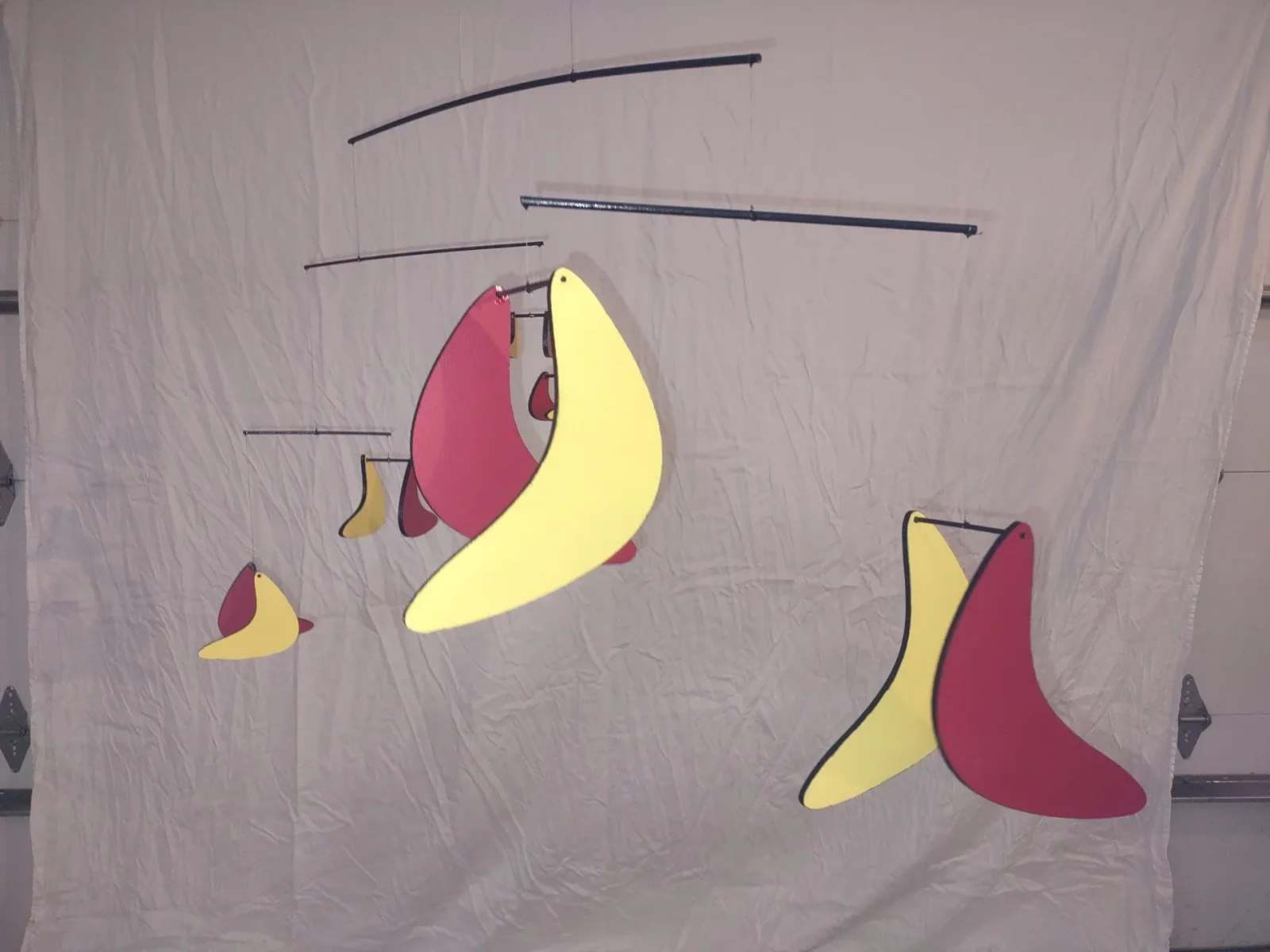 A colorful abstract metal mobile sculpture with curved, organic shapes in red and yellow.