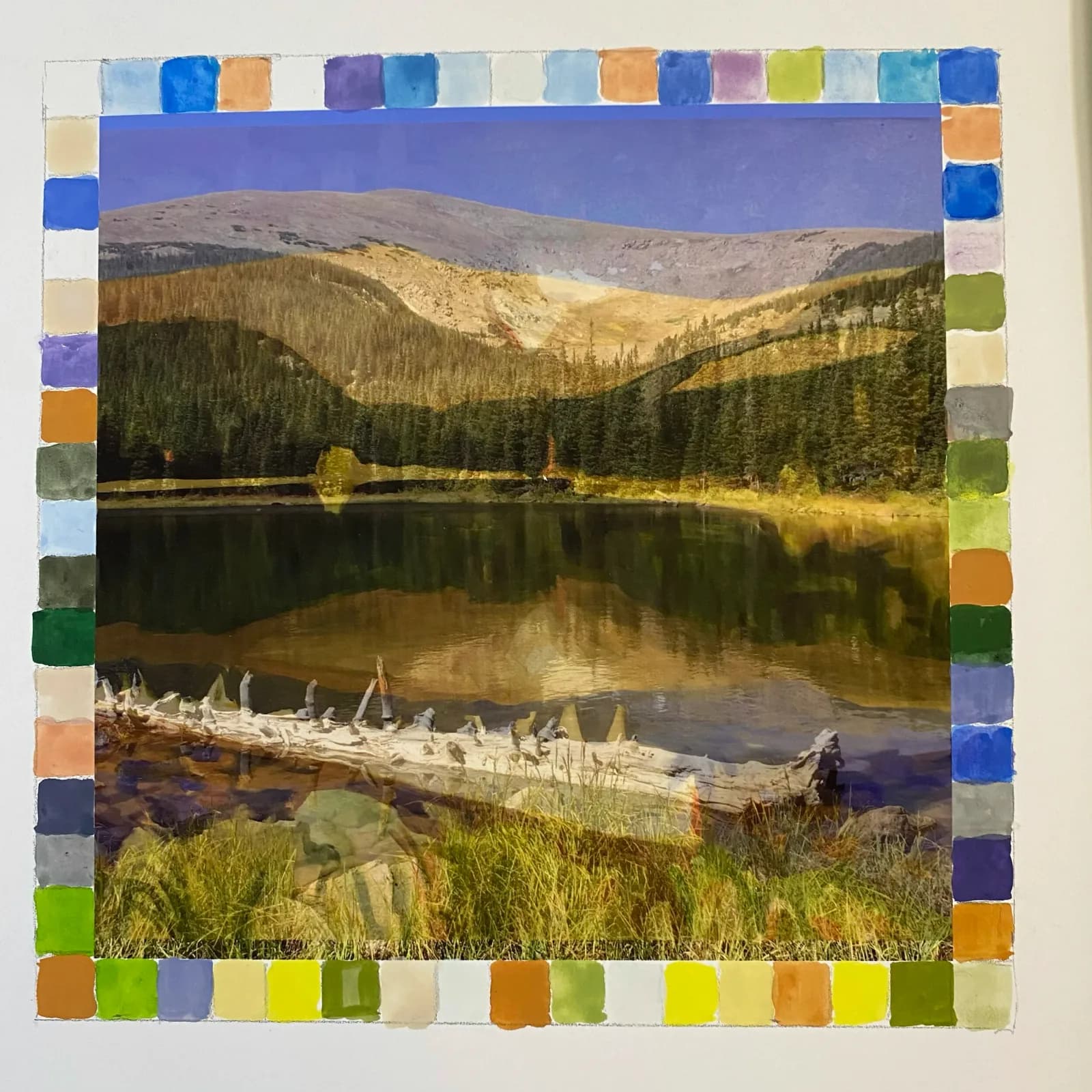 A watercolor landscape painting depicts a serene lake reflecting mountains, with a fallen log in the foreground, bordered by color swatches.