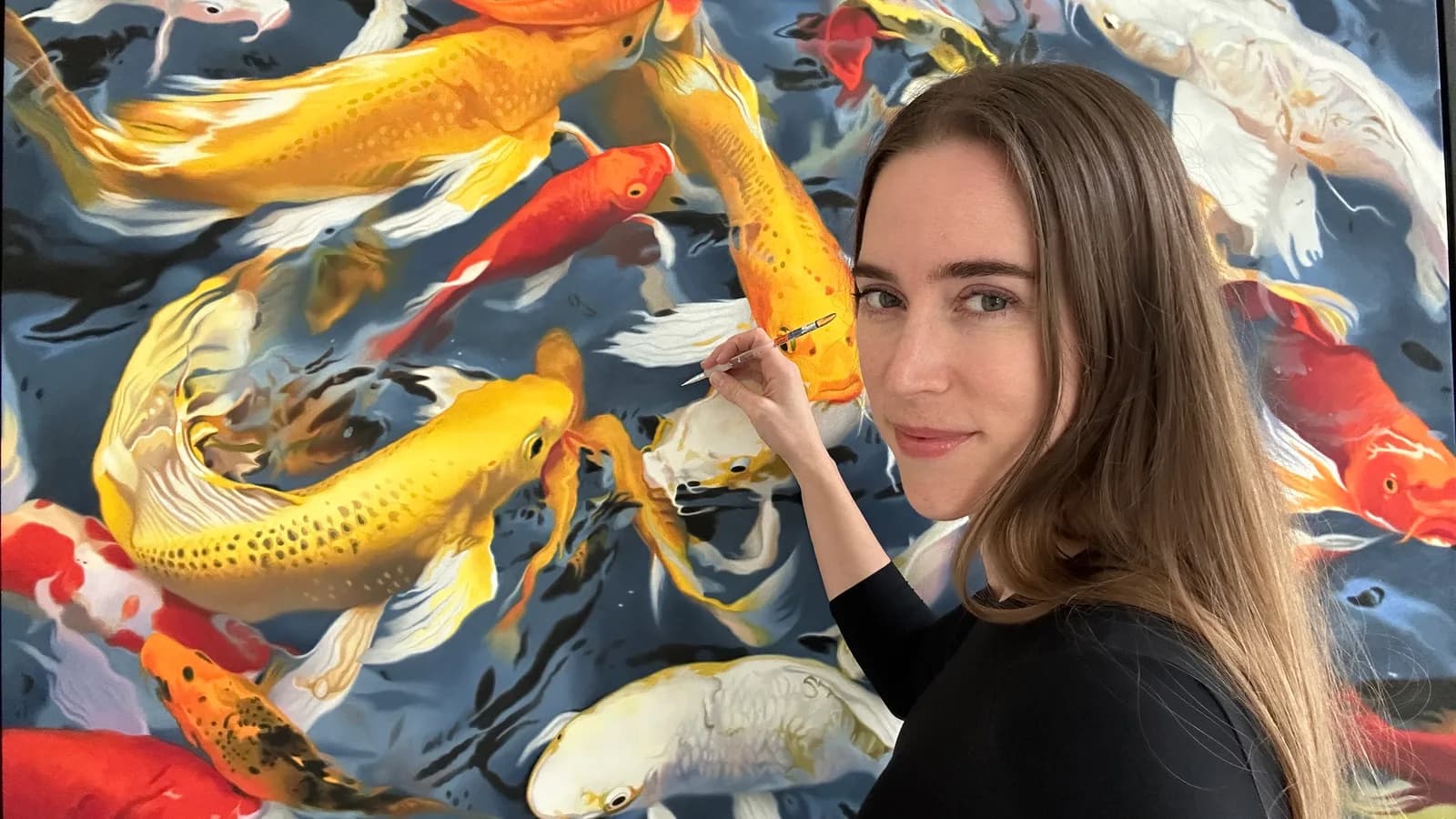 An artist works on a vibrant painting of koi fish in shades of Valencia, Dandelion, and Masala.