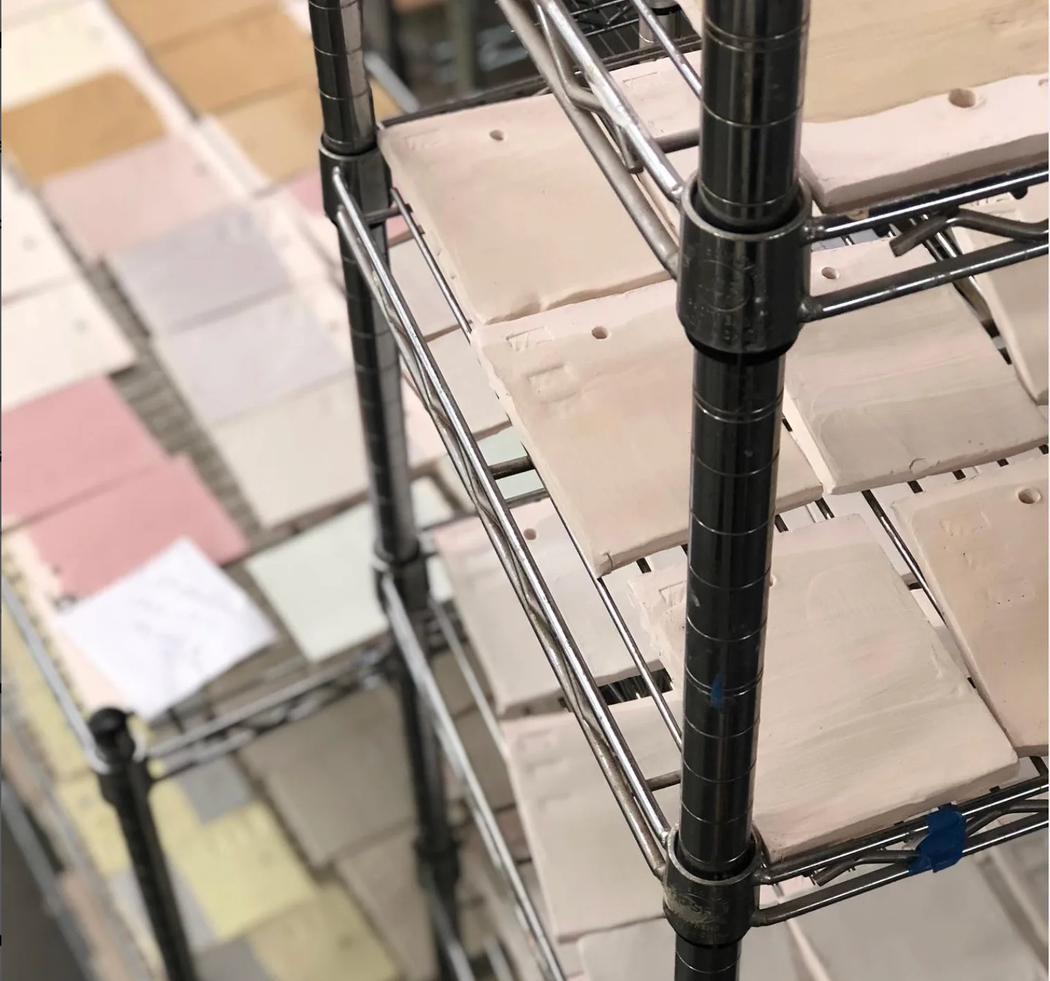 Clay samples drying on a metal rack in a studio setting.