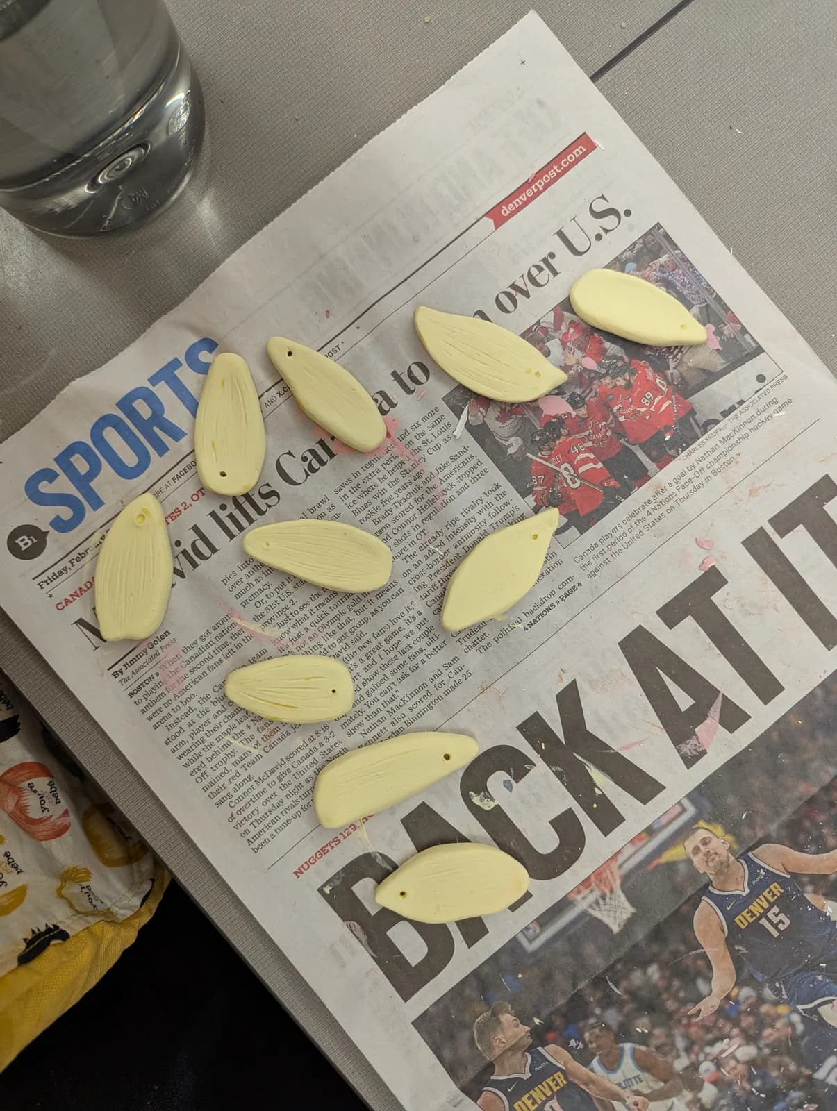 Unfired clay earring components laid out on a newspaper.