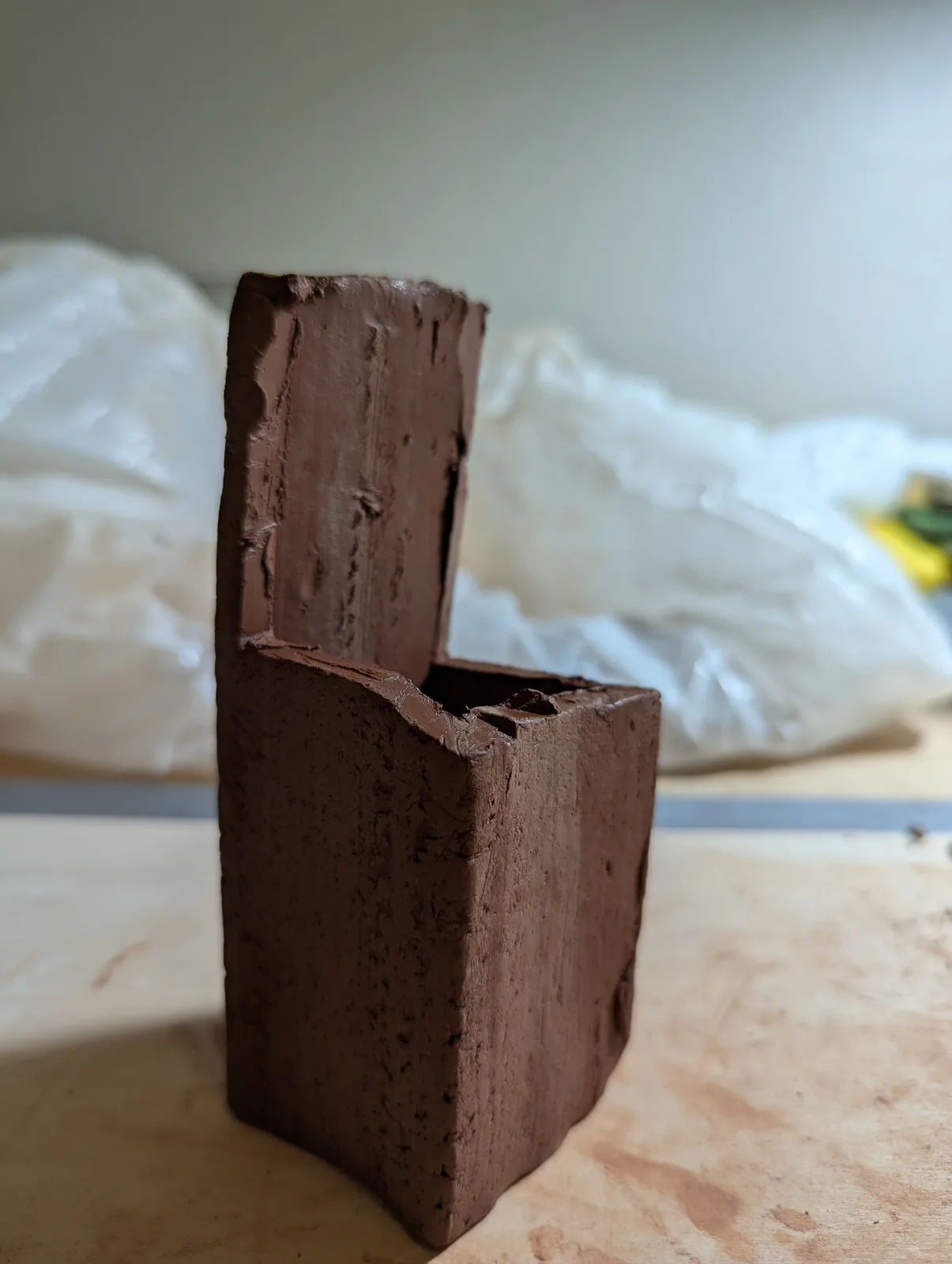 A clay sculpture in progress, showing the raw material and unfinished form in a studio setting.