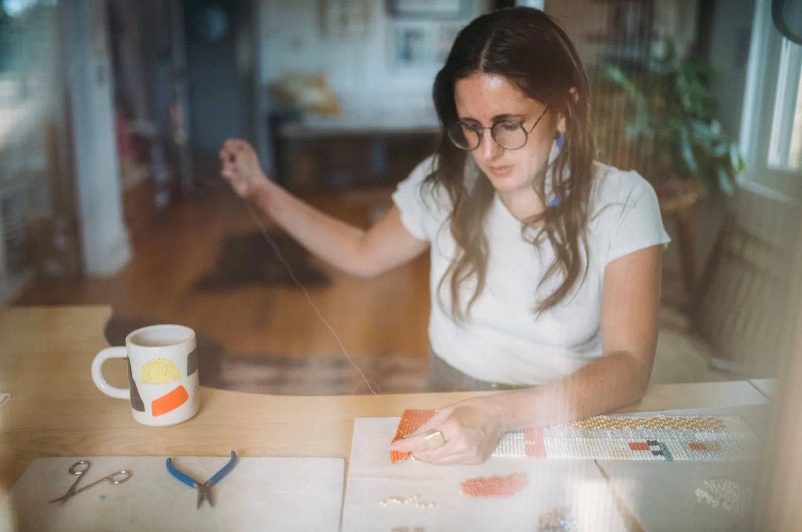 Artist beading jewelry in a studio setting with tools and materials.