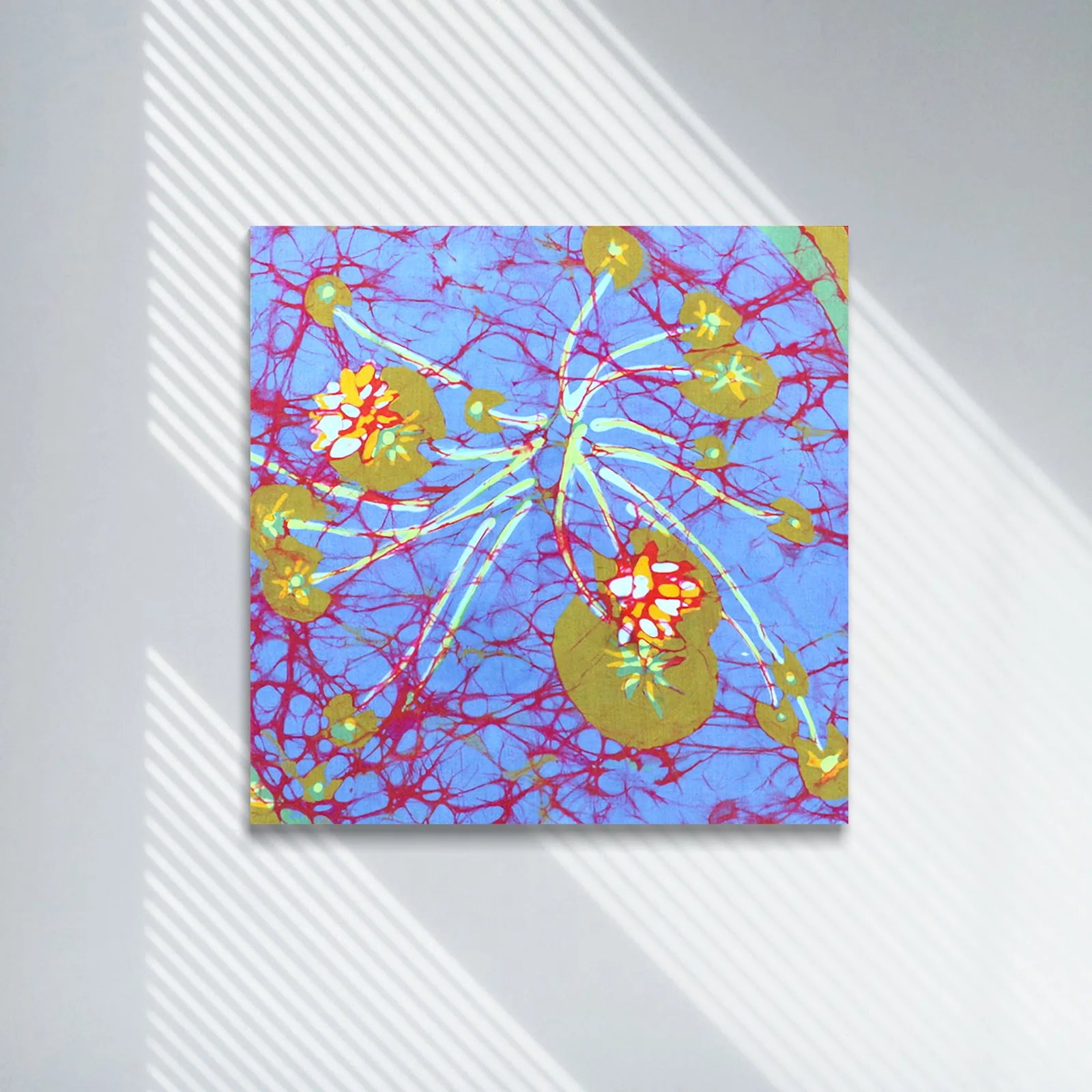 An abstract batik textile artwork depicts water lilies with vibrant red, yellow, and white accents against a blue background.