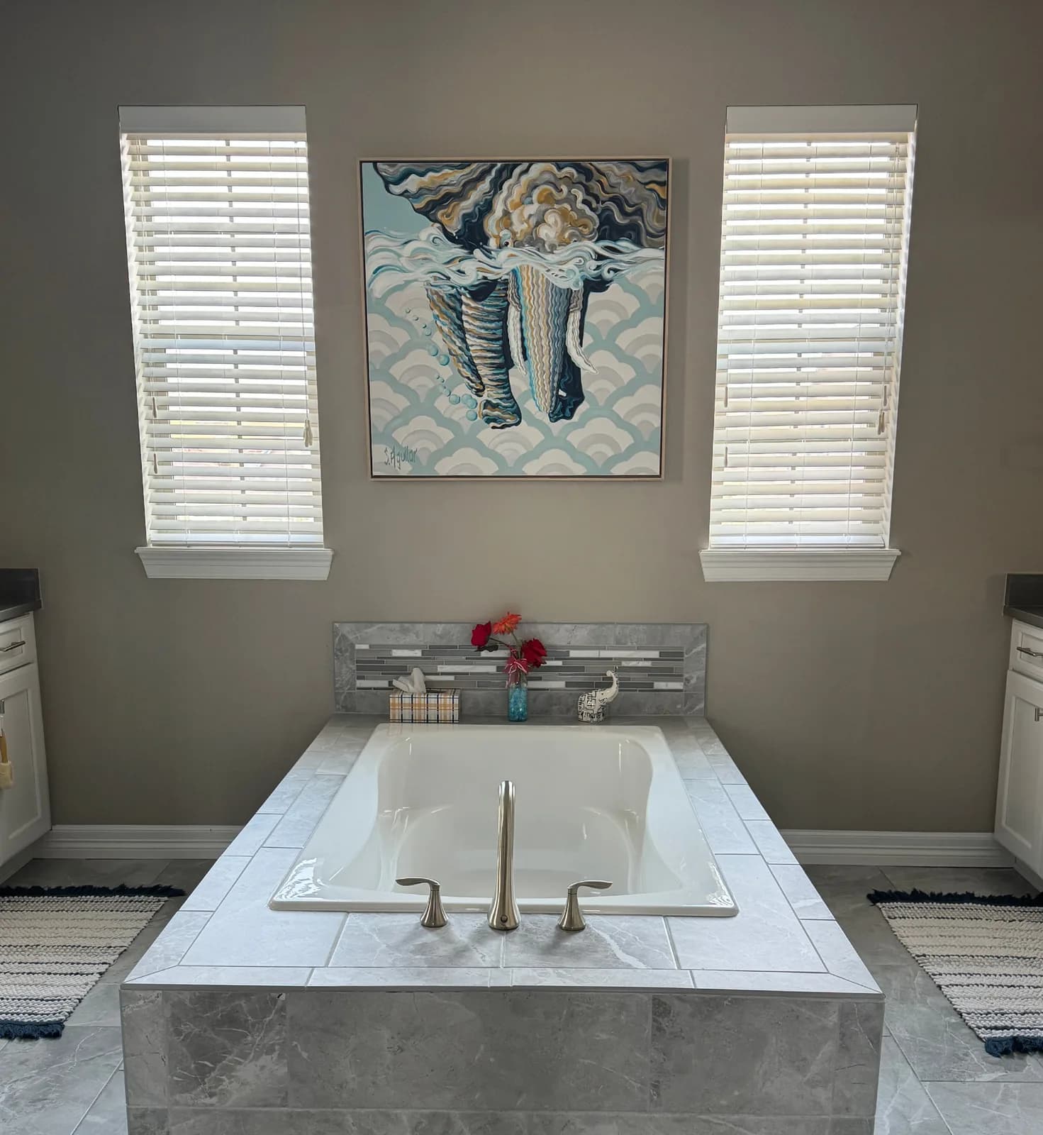 An abstract oil painting of an elephant partially submerged in water, displayed above a bathtub in a bathroom.