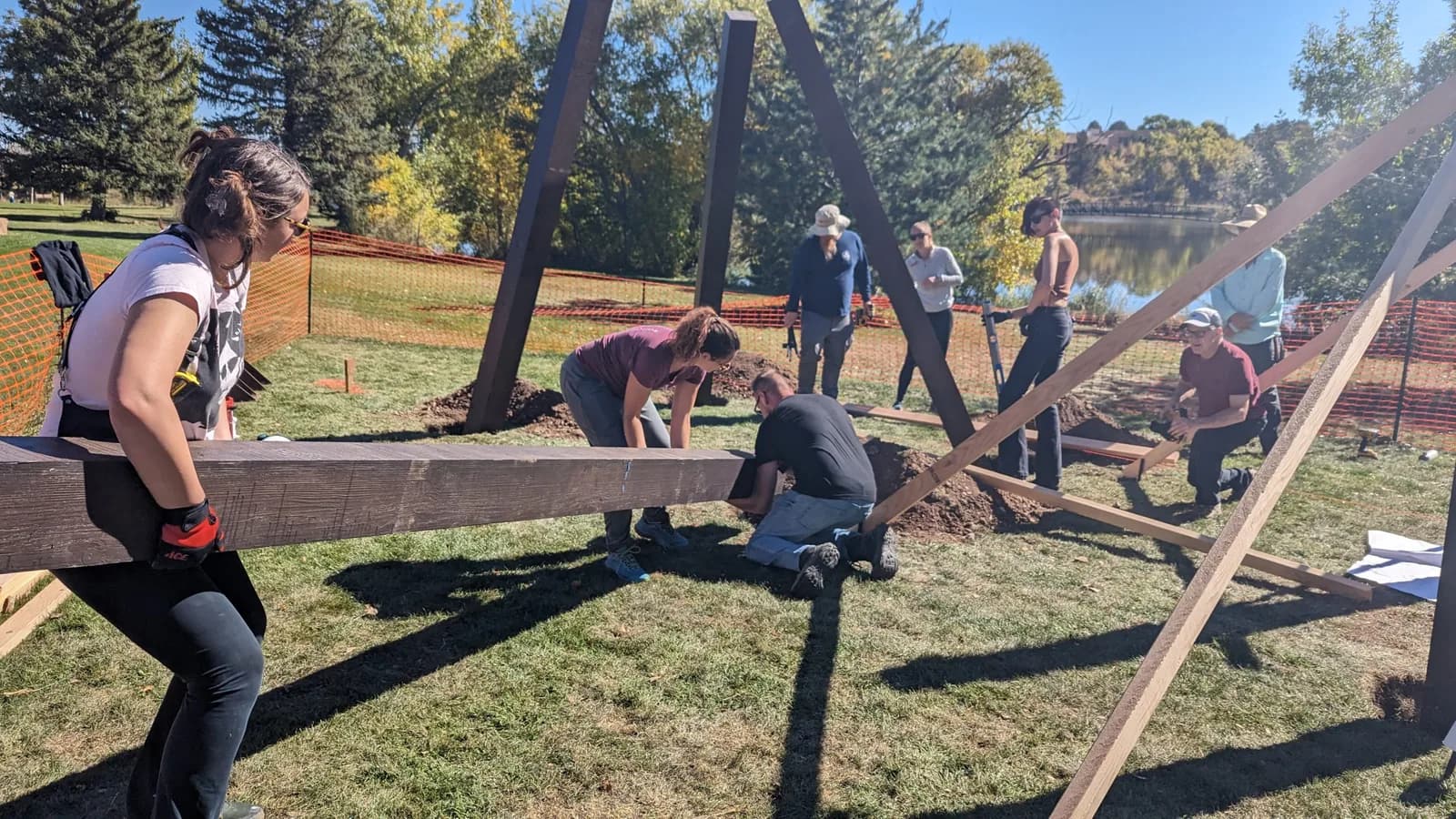 A group of people work together to construct a large wooden installation outdoors.