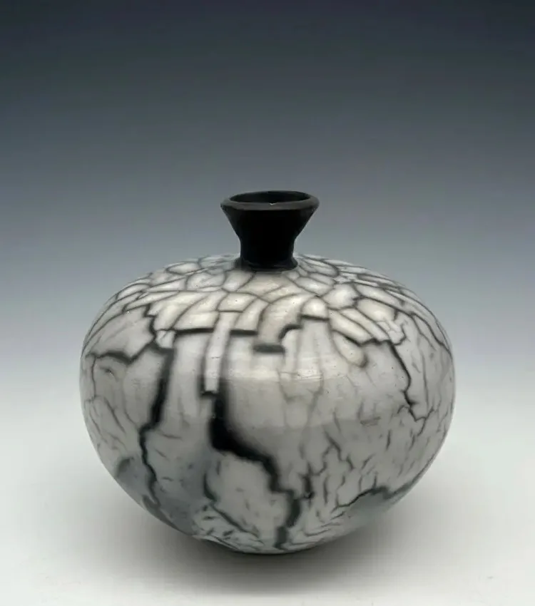 A crackle-glazed ceramic vase in shades of gray and black features a distinctive crackle pattern.